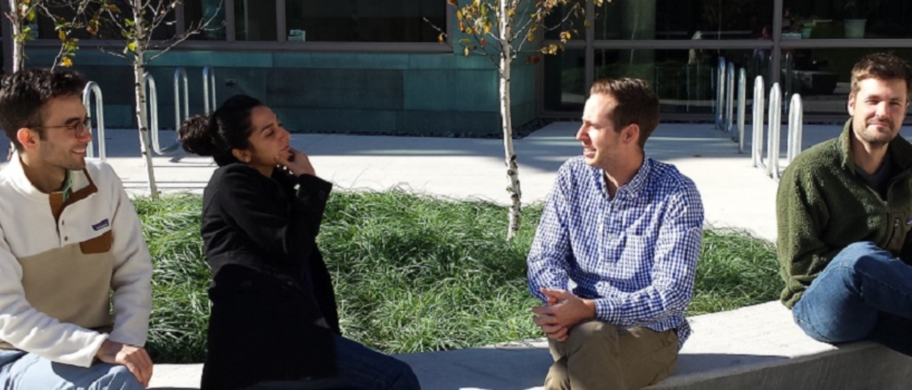 Four MSTP students sitting on a bench talking with other