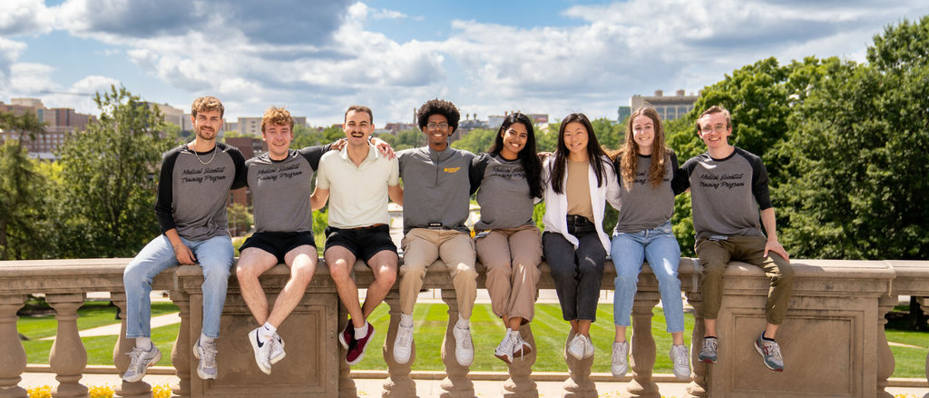 Students sit on ledge with blue sky at summer retreat